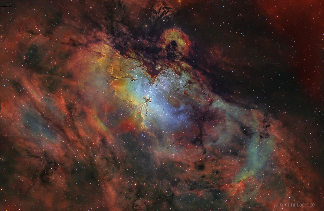 A deep image of the Eagle Nebula in many scientifically
assigned colours. The area around the nebula appears red, but 
the centre is blue with unusual pillars visible. 
Please see the explanation for more detailed information.