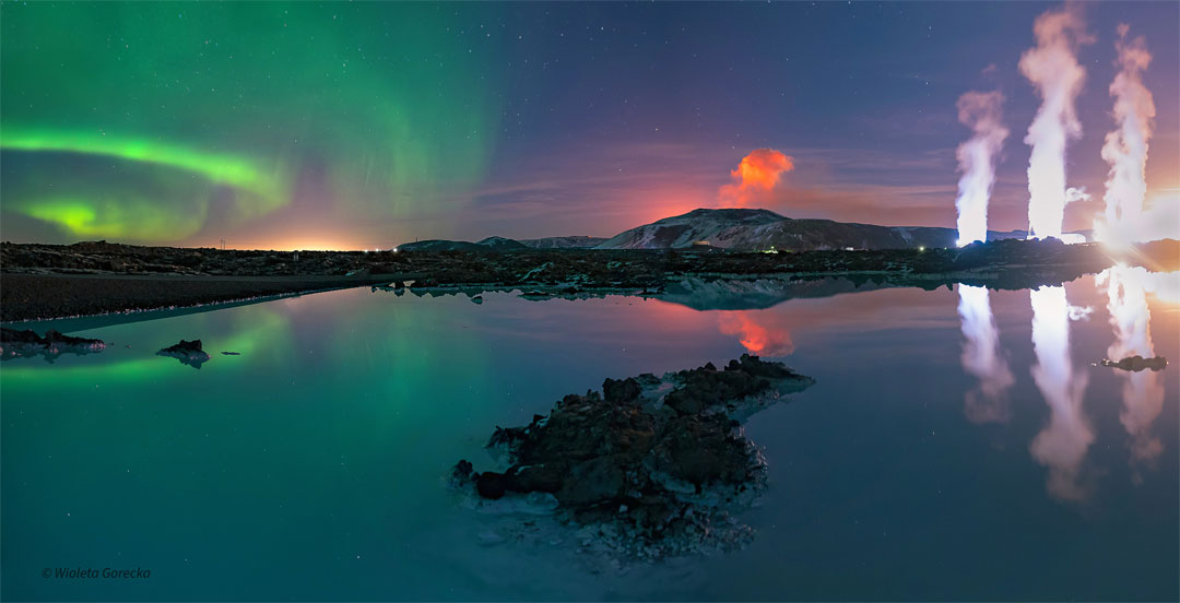 A body of water is seen in front of a night sky. The
water reflects the sky. In the sky, on the right are green
aurora. In the centre is an orange plume. On the right
are three while plumes. 
Please see the explanation for more detailed information.