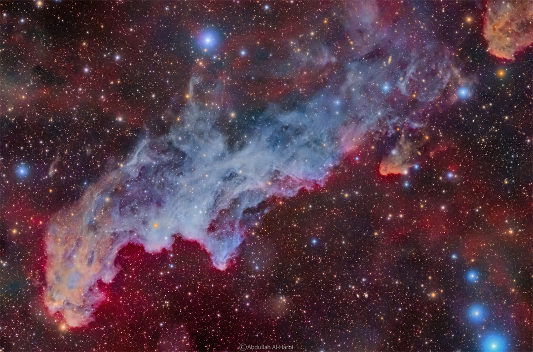 A colourful star field surrounds a big blue reflection nebula.
The nebula is elongated across the wide frame and said to 
resemble the head of folklore-based witch.
Please see the explanation for more detailed information.