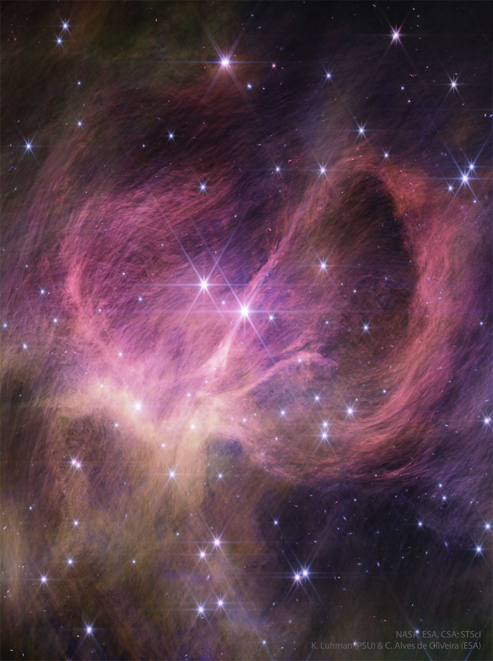 A cluster of stars is shown along with surrounding nebular gas a
and dust. Shown in infrared light in pink, the dust winds around the 
nebula centre and itself appears composed of many finer filaments.
Please see the explanation for more detailed information.
