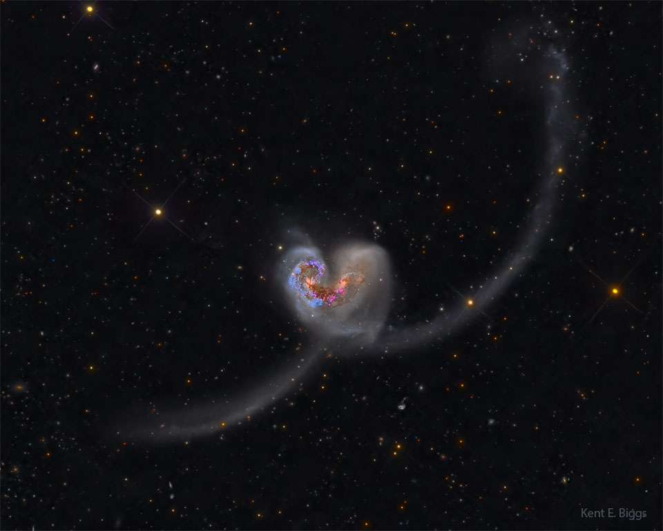 Two galaxies are seen colliding the image centre. 
Together, they look like a classic heart icon but with
long tails. 
Please see the explanation for more detailed information.