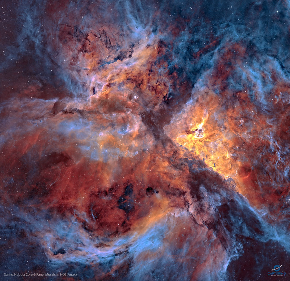 A star field strewn with filaments of dust and gas
is shown: the centre of the Carina Nebula. Shown in 
colours emitted by specific elements, the frame shows
blue gas around the edges and orange and red coloured
gas in the centre. Dark dust laces the busy frame. 
Please see the explanation for more detailed information.
