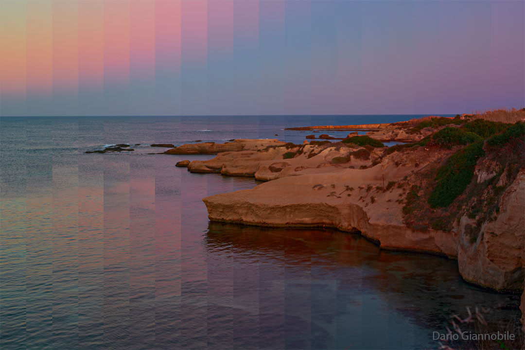 A rocky shoreline is shown with land on the right and water 
on the left. Above is a sky that shows unusually pixelated and coloured
vertical bands.  
Please see the explanation for more detailed information.