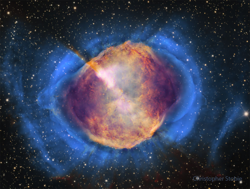 A starfield is shown with a frame dominated by a gaseous
nebula. The nebula, filled with structure, appears orange 
in the centre but blue
around the edges. 
Please see the explanation for more detailed information.