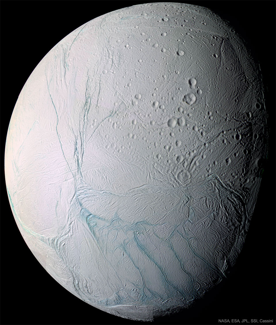 A light-coloured spherical body is shown mostly illuminated
against a dark background. Many craters are visible. Unusual
blue stripes meander on the surface. 
Please see the explanation for more detailed information.