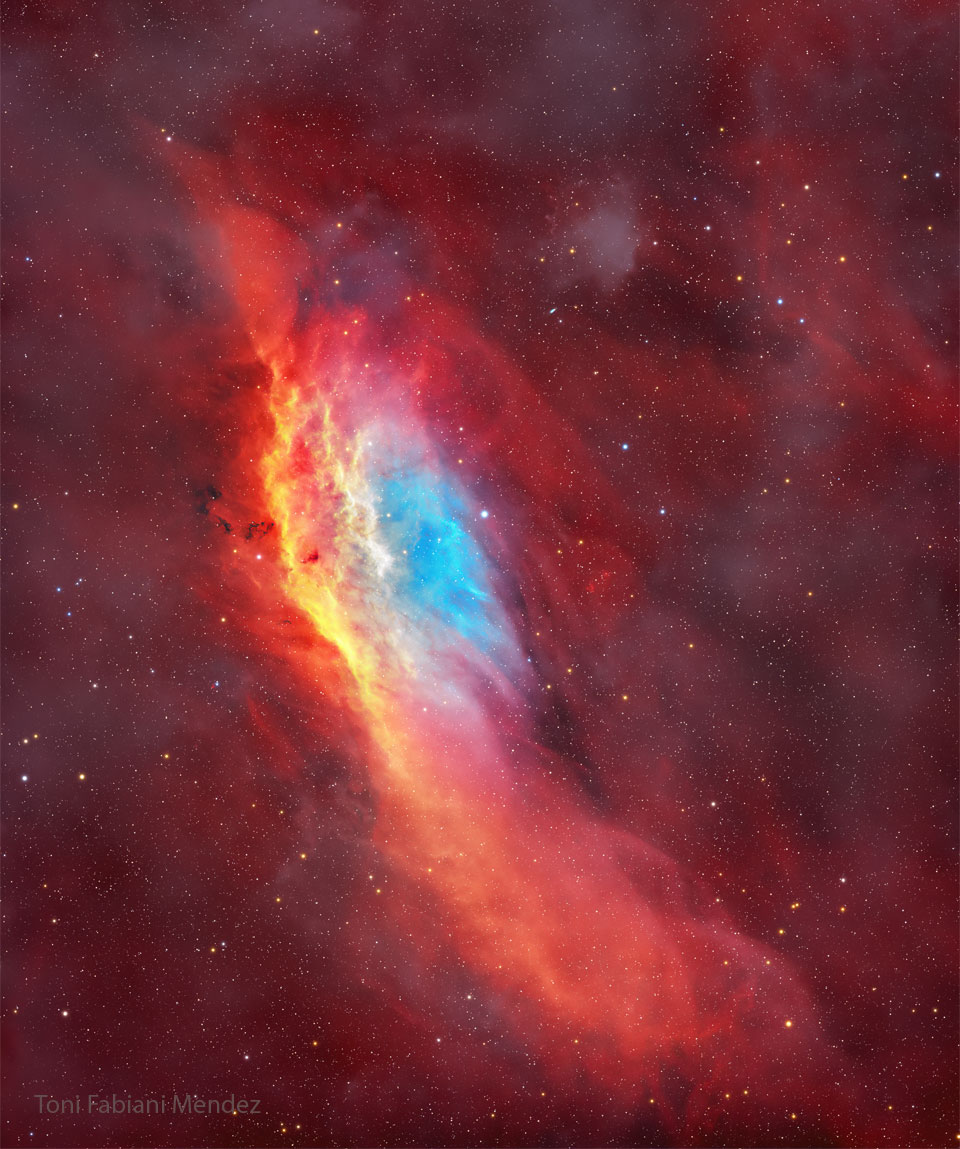 The starry image filled with a red glow features 
a red, yellow, and blue coloured nebula. The nebula 
has, roughly, the shape of the US state of California.
Please see the explanation for more detailed information.