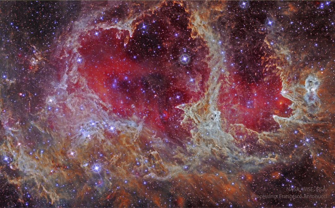 A star field is shown in infrared light. In the centre
is an extremely complex nebula that is outlines an iconic
heart. Glowing gas shades the centre of the heart red.
Please see the explanation for more detailed information.