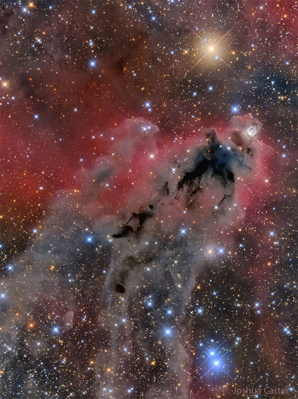 An image of a foreboding dark nebula before a red-glowing gas 
background and many bright and colourful stars.
Please see the explanation for more detailed information.