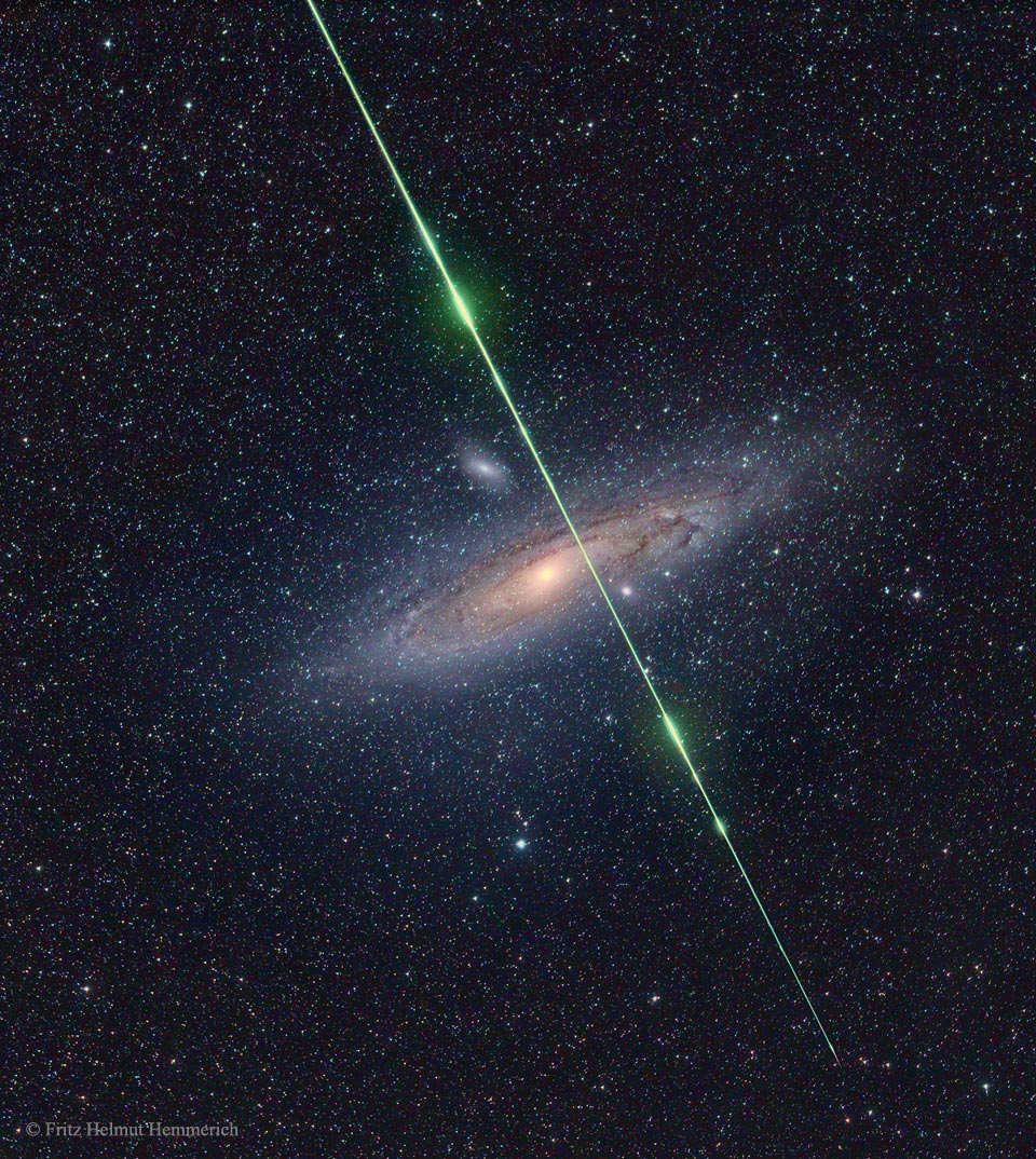 A starfield has the Andromeda galaxy in the centre.
Streaking down from the top is a green line with several
bright segments -- a meteor captured coincidently.
Please see the explanation for more detailed information.