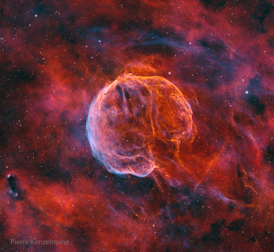 A colourful starfield surrounds a giant nearly-spherical 
nebula that has texture and stripes like watermelon. 
The lower right of the nebula is open making it appear
like a medulla oblongata -- the stem that connects to 
a brain. 
Please see the explanation for more detailed information.