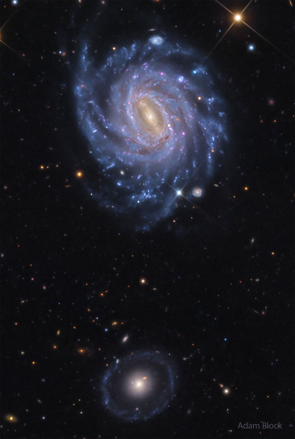 A starfield is shown showing two prominent galaxies. 
Near the top is a bright spiral galaxy with several blue
spiral arms. Near the bottom is a fainter circular 
galaxy with a bright centre. 
Please see the explanation for more detailed information.