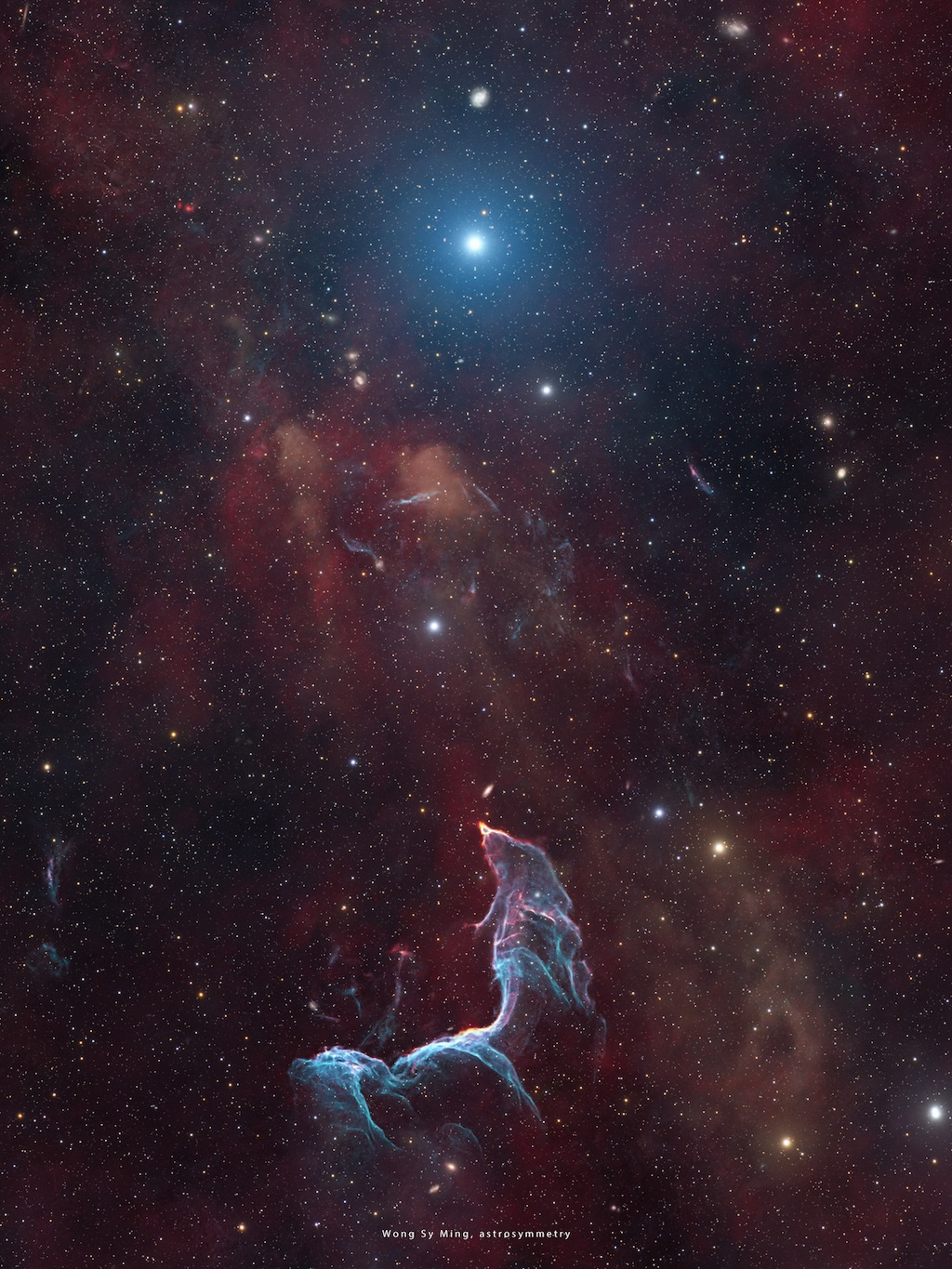 A delicate nebula in shades of blue and purple
	  shines in front of a dark field of stars.
	  The shape of the nebula resembles a mermaid.